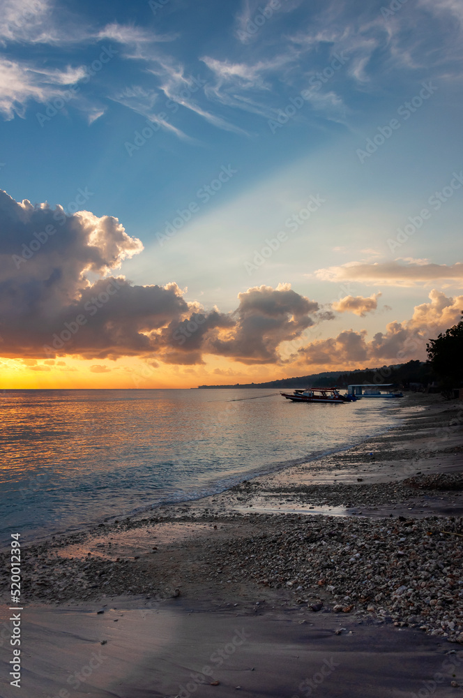 Beautiful bright dawn with colored clouds in the sky over the sea, ocean. Sandy coastline, beach, lush clouds. Summer tropical natural background. Travel concept. Nusa Penida Island, Indonesia