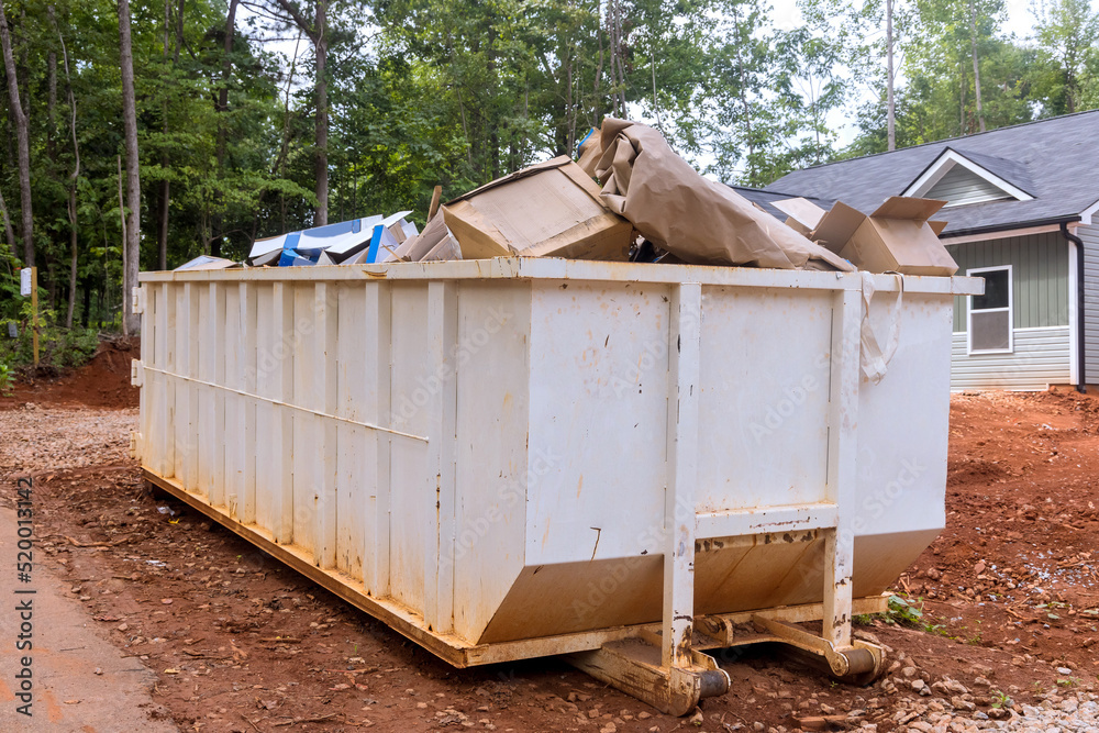 Construction site a rubbish removal container on house underneath an industrial building is used for waste disposal Construction site a rubbish removal container on house underneath an industrial building is used for waste disposal