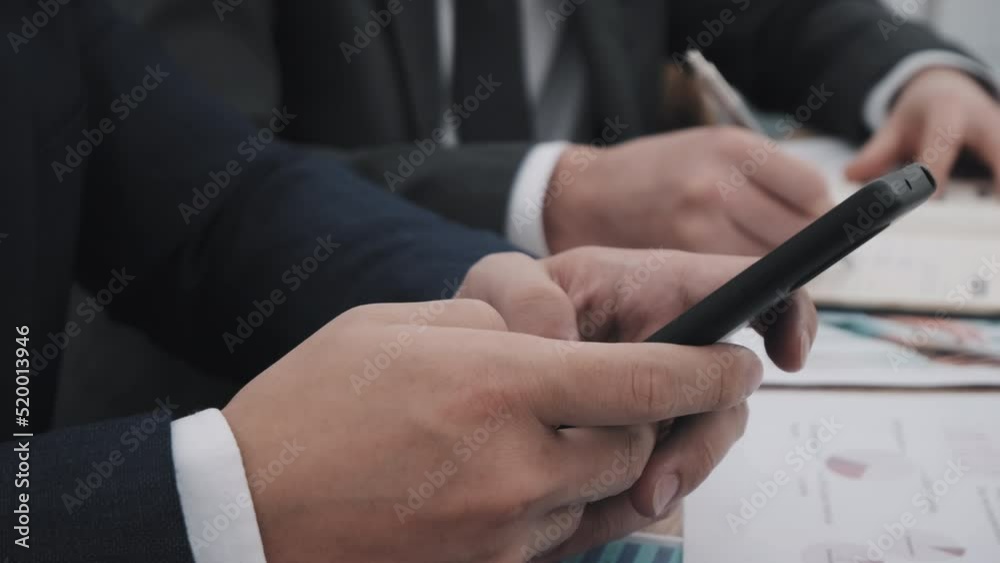 Side view of cropped businessman sitting at desk, using smartphone Side view of cropped businessman sitting at desk, using smartphone