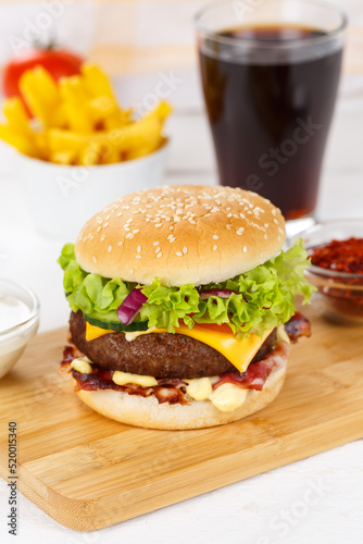 Hamburger Cheeseburger meal fastfood fast food with cola drink and French Fries on a wooden board portrait format
