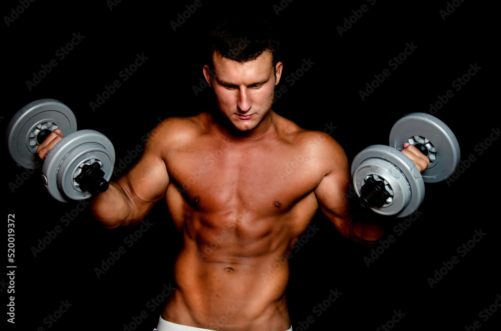 Young attractive sportsman with dumbbells. Male athletic body.	