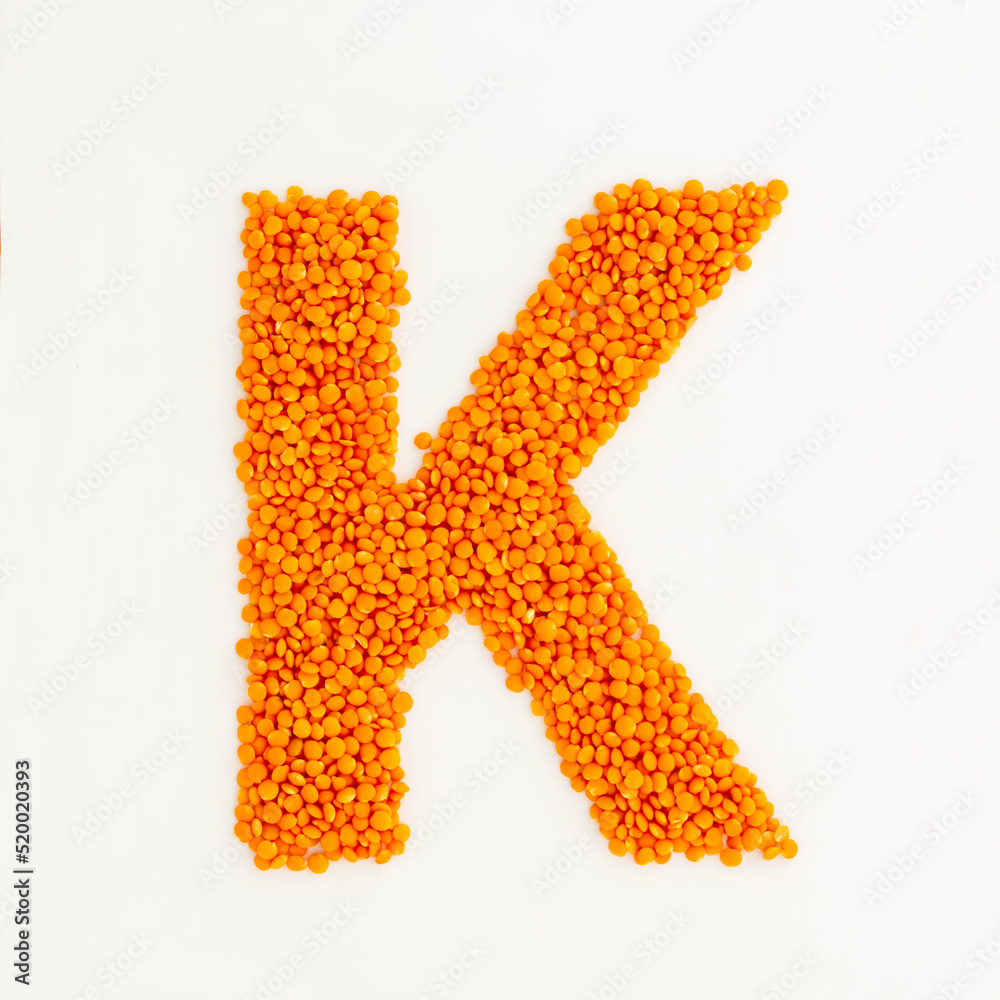 Capital letter K made from red lentils. Lentil font. White background. Bright font for menu or food blog. Lettering design element. Init cap Capital letter K made from red lentils. Lentil font. White background. Bright font for menu or food blog. Lettering design element. Init cap