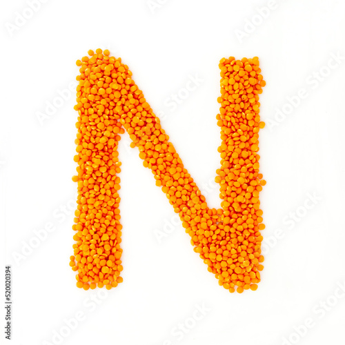 Capital letter N made from red lentils. Lentil font. White background. Bright font for menu or food blog. Lettering design element. Init cap photo