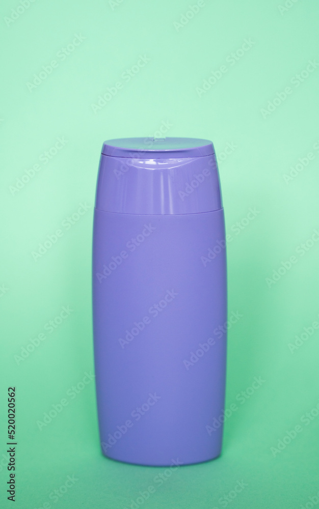 Violet plastic bottle of body care and beauty products. Studio photography of plastic bottle for shampoo, shower gel, creme isolated on green background. Violet plastic bottle of body care and beauty products. Studio photography of plastic bottle for shampoo, shower gel, creme isolated on green background.
