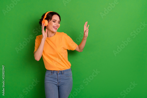 Photo of positive cheerful person have fun good mood dancing touch headphones isolated on green color background