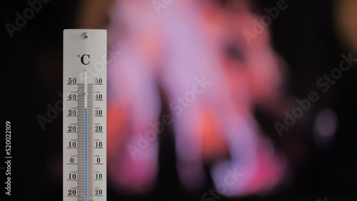 Thermometer with a fire in the background shows increasing temperature.