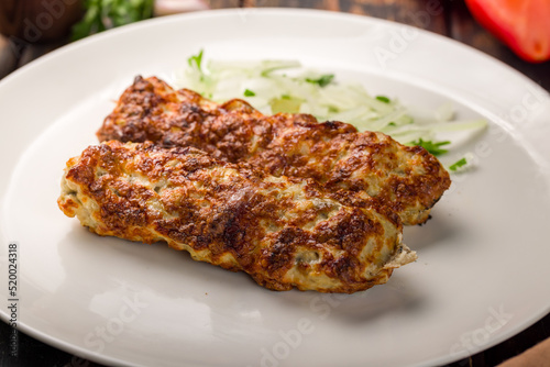 Lula kebab chicken on white plate on wooden table macro close up