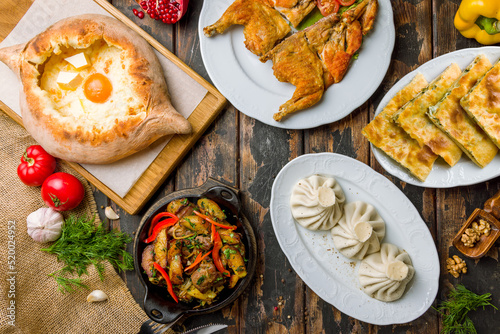 ajara Khachapuri with cheese, egg and butter, odjakhuri with pork, chicken tabacco,khinkali and khachapuri with spinach georgian kitchen on wooden table top view
