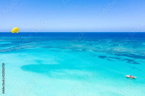 Parasailing tourists above caribbean sea. Tropical vacation. Dominican Republic. Aerial view