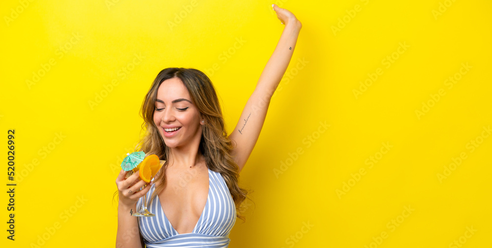 Young caucasian woman isolated on yellow background in swimsuit and holding a cocktail Young caucasian woman isolated on yellow background in swimsuit and holding a cocktail