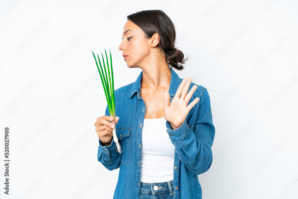 Young hispanic woman holding chive isolated on white background making stop gesture and disappointed Young hispanic woman holding chive isolated on white background making stop gesture and disappointed