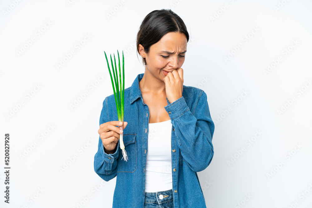 Young hispanic woman holding chive isolated on white background having doubts Young hispanic woman holding chive isolated on white background having doubts