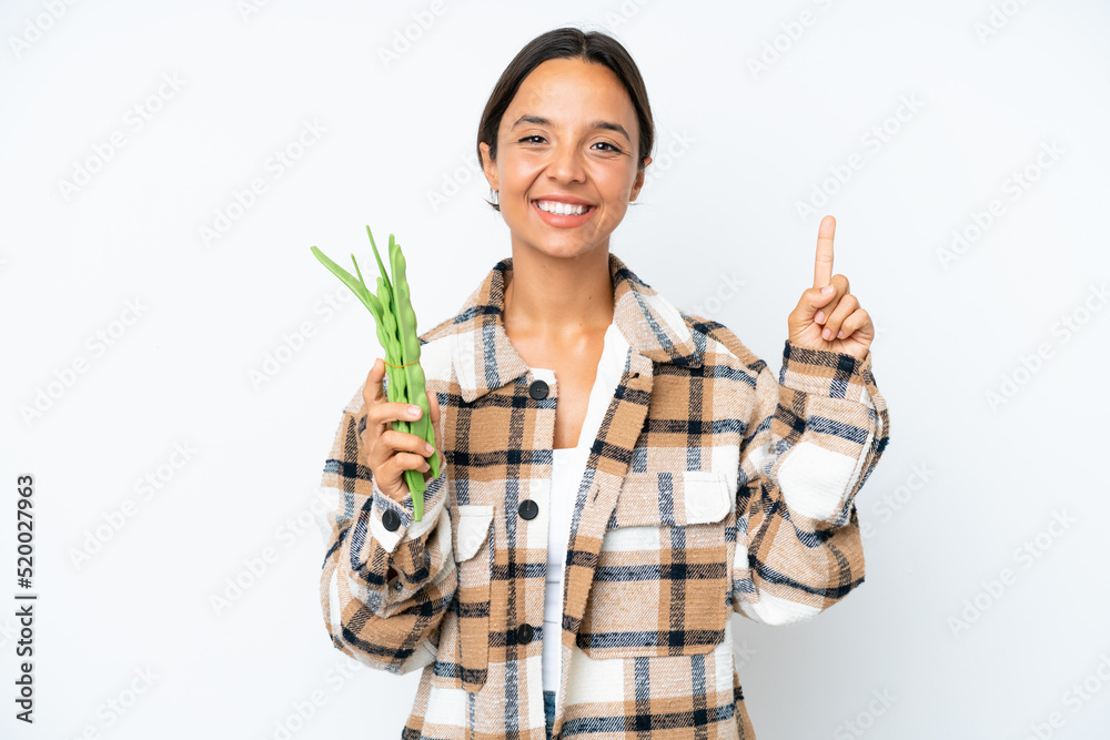 Young hispanic woman holding a green beans isolated on white background pointing finger to the side and presenting a product Young hispanic woman holding a green beans isolated on white background pointing finger to the side and presenting a product
