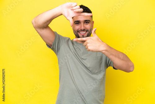 Young Arab handsome man isolated on yellow background focusing face. Framing symbol