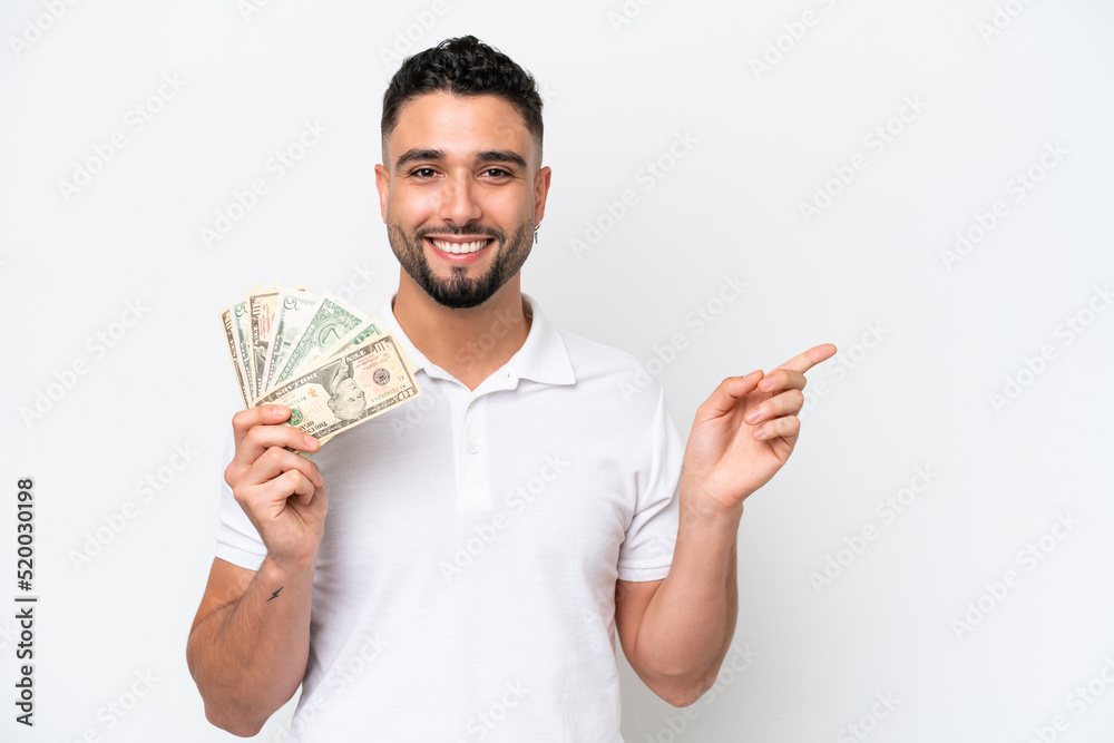 Young Arab man taking a lot of money isolated on white background pointing finger to the side Young Arab man taking a lot of money isolated on white background pointing finger to the side