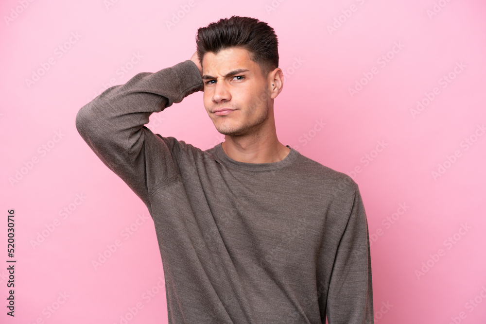 Young caucasian man isolated on pink background having doubts