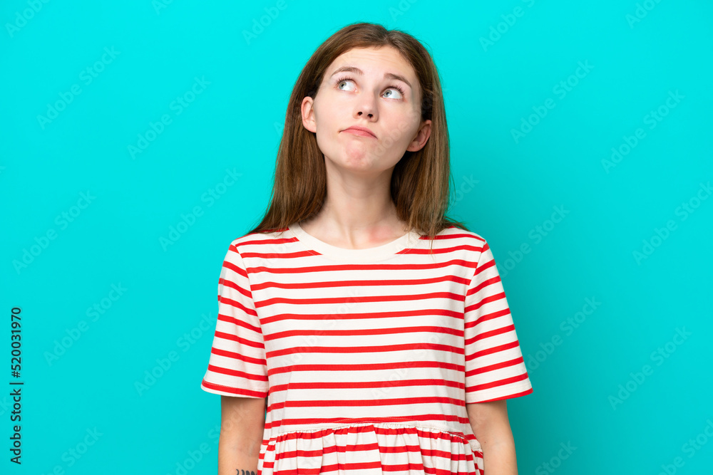 Young English woman isolated on blue background and looking up Young English woman isolated on blue background and looking up