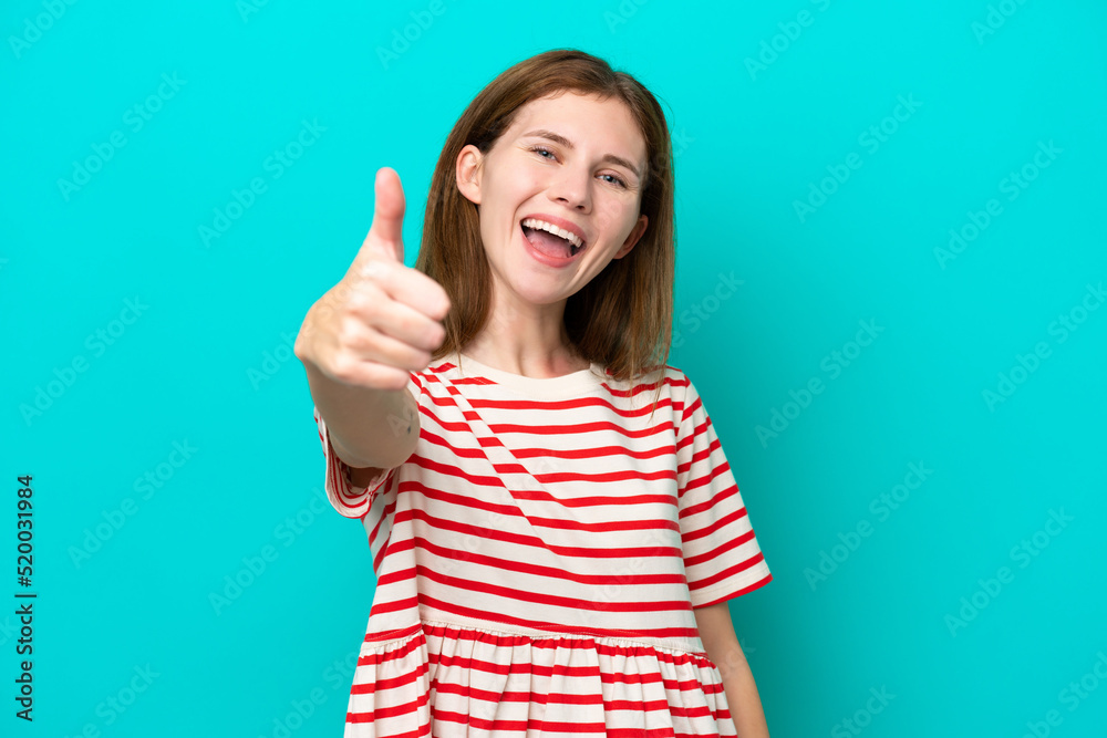 Young English woman isolated on blue background with thumbs up because something good has happened Young English woman isolated on blue background with thumbs up because something good has happened
