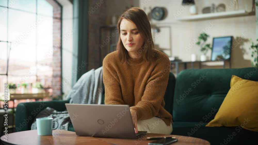 Portrait of Smiling Young Woman Working from Home on Laptop Computer in Sunny Cozy Apartment. Successful Creative Girl Entrepreneur Does Remote for e-Business Project, Online Shopping. Arc Shot Portrait of Smiling Young Woman Working from Home on Laptop Computer in Sunny Cozy Apartment. Successful Creative Girl Entrepreneur Does Remote for e-Business Project, Online Shopping. Arc Shot