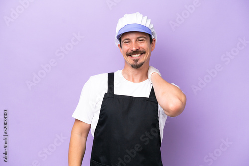 Fishmonger man wearing an apron isolated on purple background laughing