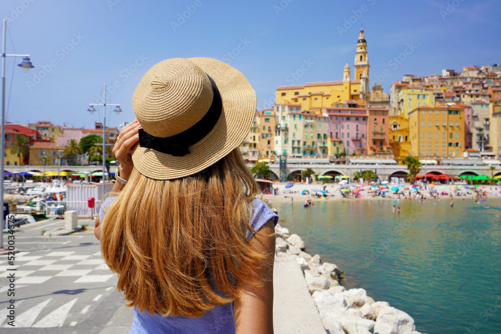 Summer holiday in France. Back view of young woman with long hair and hat in Menton, French Riviera.