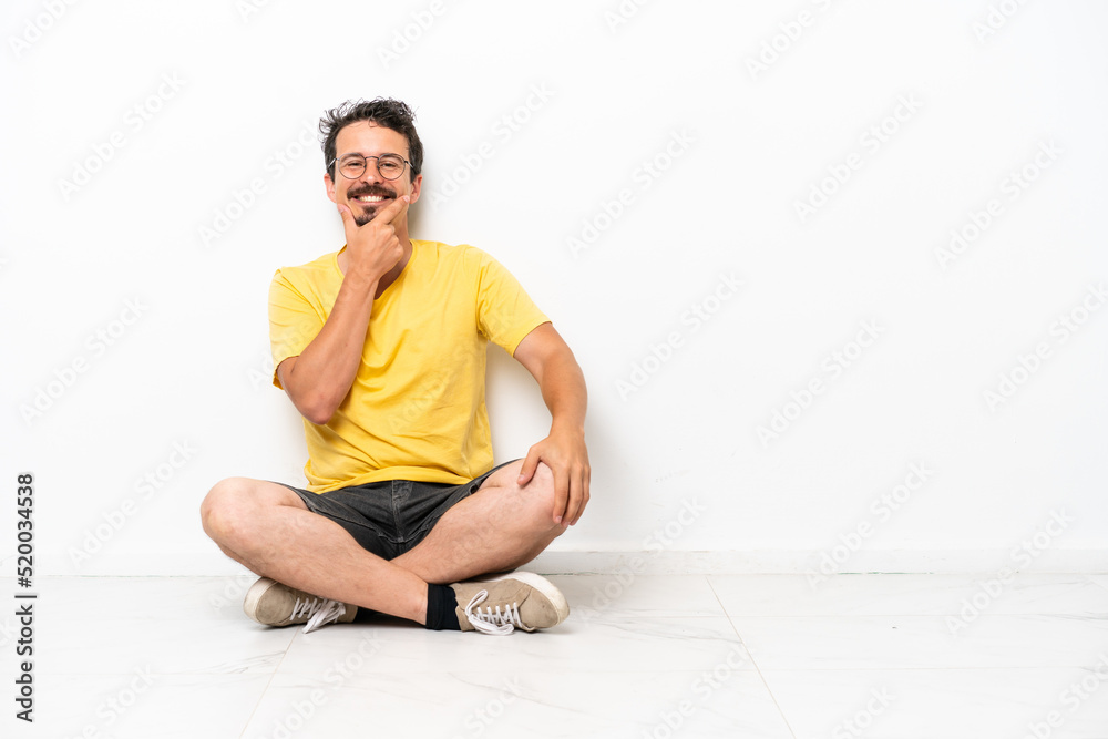 Young caucasian man sitting on the floor isolated on white background smiling Young caucasian man sitting on the floor isolated on white background smiling