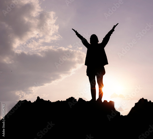Silhouette of a woman praying over a beautiful sky. Hypnosis concept.