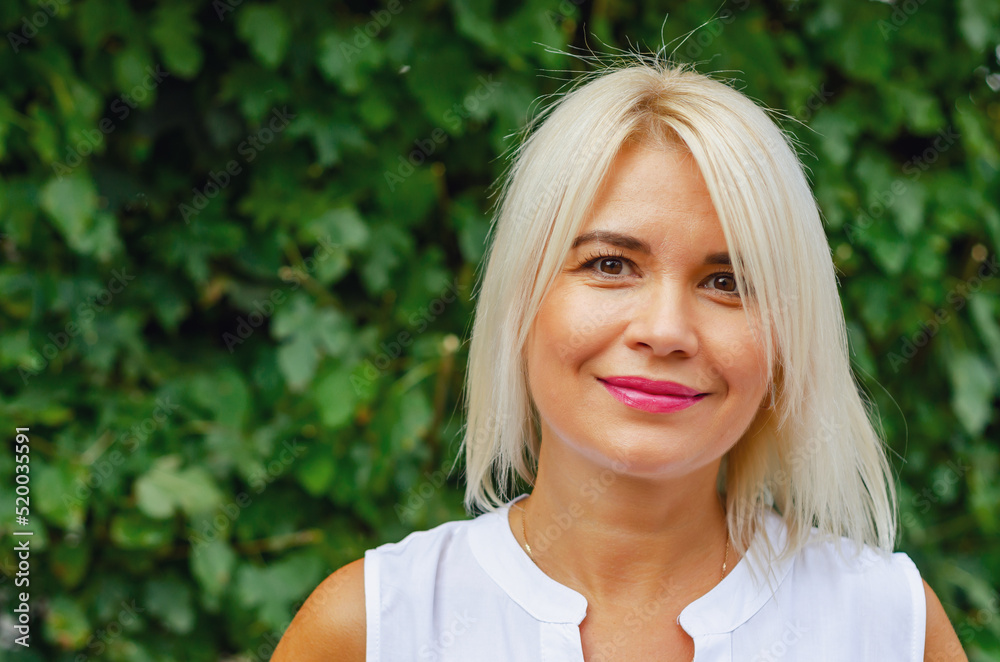 Portrait of a middle-aged woman against a background of green leaves. Success, antiaging Portrait of a middle-aged woman against a background of green leaves. Success, antiaging