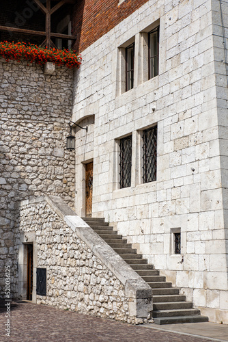 Biały średniowieczny budynek z kamienia. Wejście do budynku po kamiennych schodach.