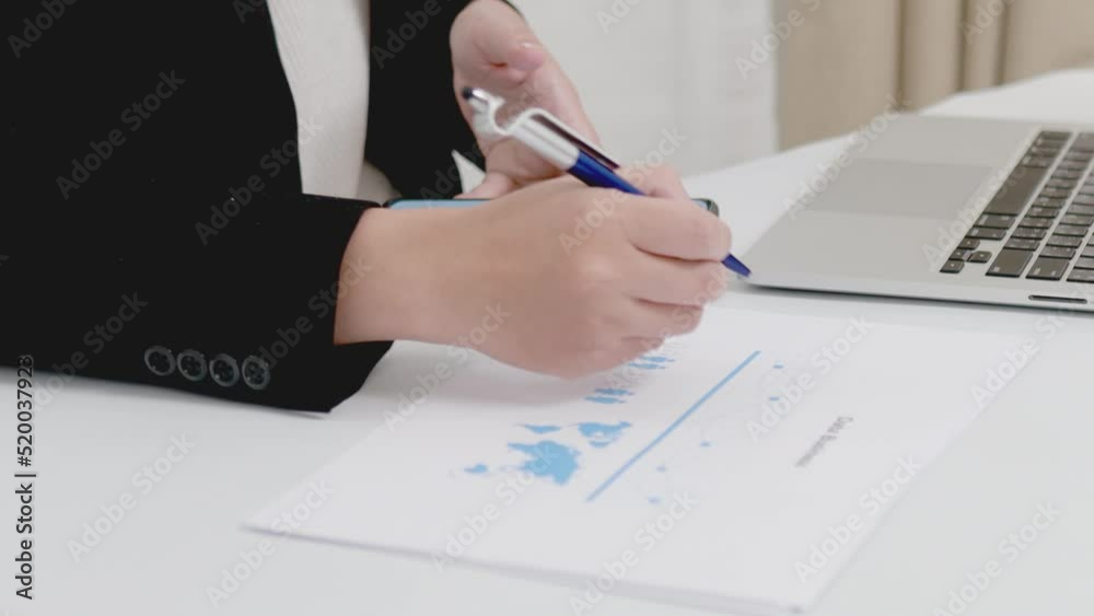 Close-up of businesswoman or accountant holding pen working with document and laptop computer on the table, Accounting financial business report to analyze and plan investment financial data. Close-up of businesswoman or accountant holding pen working with document and laptop computer on the table, Accounting financial business report to analyze and plan investment financial data.