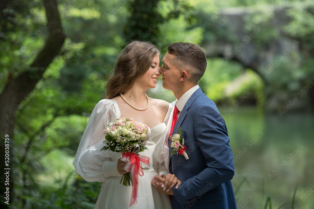 a guy in a suit and a girl in a white dress are standing in the forest and hugging. a guy in a suit and a girl in a white dress are standing in the forest and hugging.