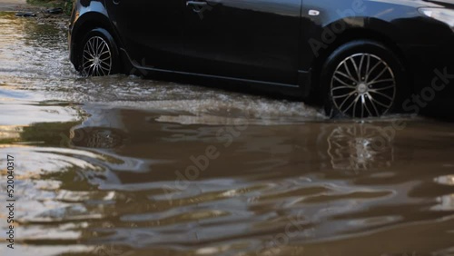 City roads flooded by a downpour. The car drives through a huge puddle.