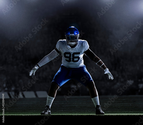 Large American Football player standing imposing and strong on the field in a football stadium ready to make a tackle. Big, tough and athletic professional football player. photo