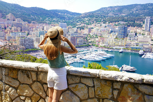 Beautiful stylish girl enjoying view of Monte-Carlo cityscape with skyscrapers and yachts in the harbor, Principality of Monaco