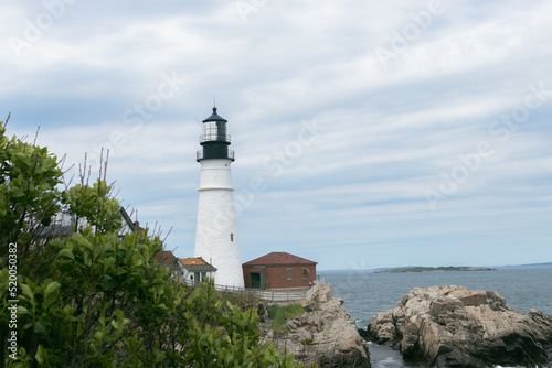 Lighthouse on coast during day against cloudy sky