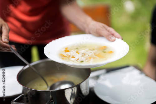 Woman Hands Serving a Vegetable Soup at Lunch Time Outdoors
