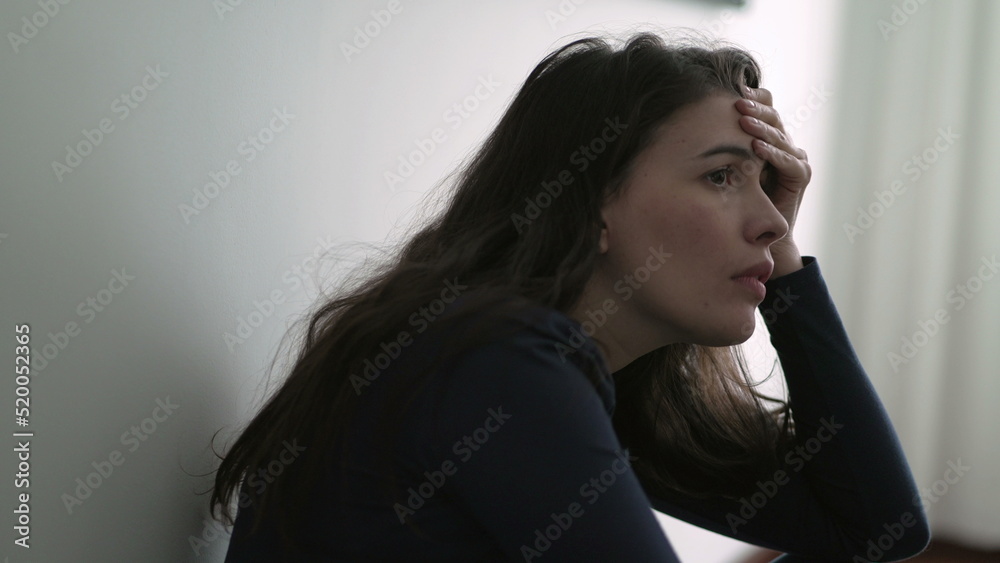 Nervous woman suffering from depression sitting on floor. Frustrated person in mental anguish feeling regret Nervous woman suffering from depression sitting on floor. Frustrated person in mental anguish feeling regret
