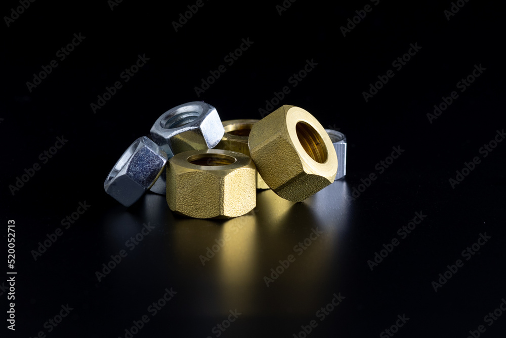 Group of Silver and Gold Hardware Nuts on Reflective Black Surface Group of Silver and Gold Hardware Nuts on Reflective Black Surface
