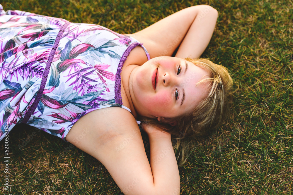Trisomy 21 child having fun outside in summer season lay in the ground Trisomy 21 child having fun outside in summer season lay in the ground