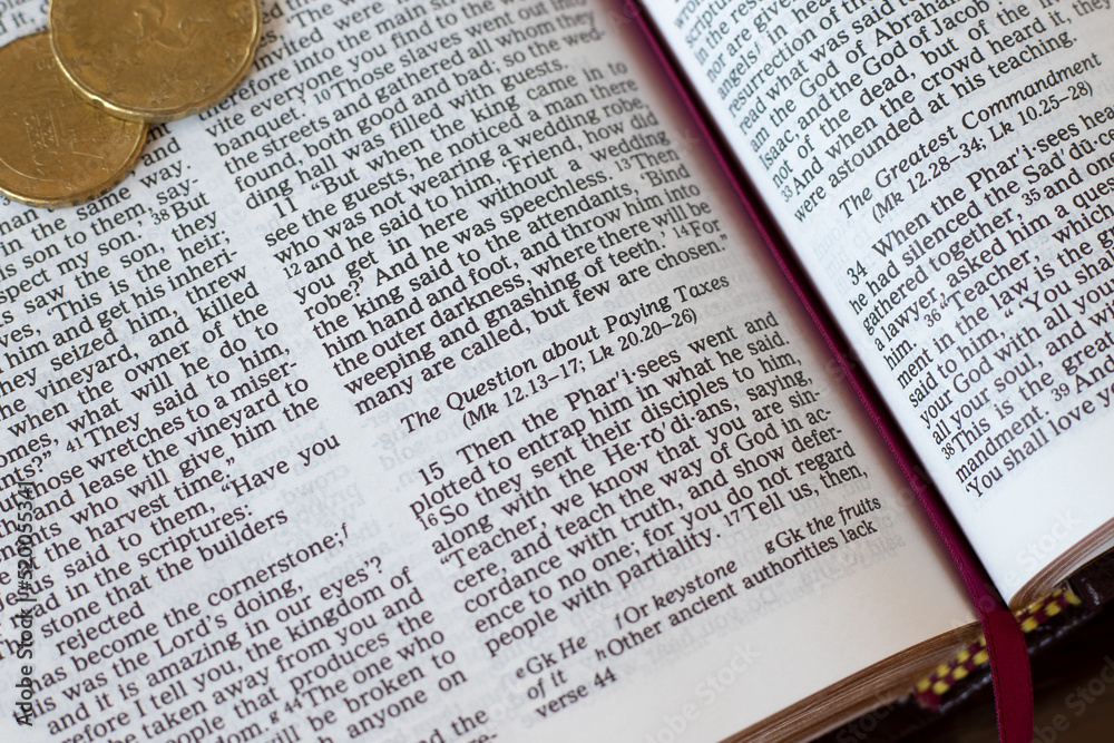 Open holy bible book page with verses for paying taxes and golden coins