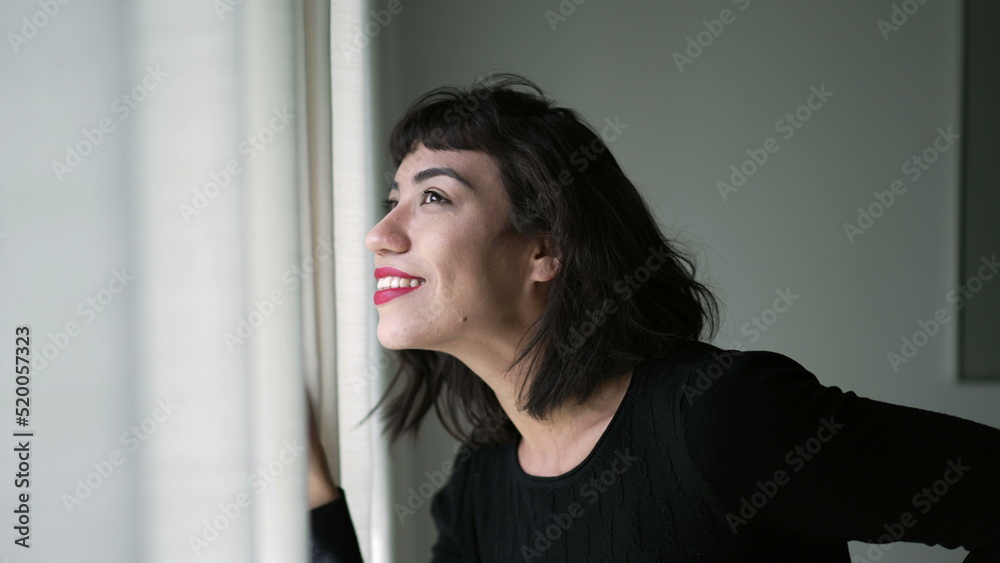 One beautiful hispanic girl looking out through curtain window checking sunlight day