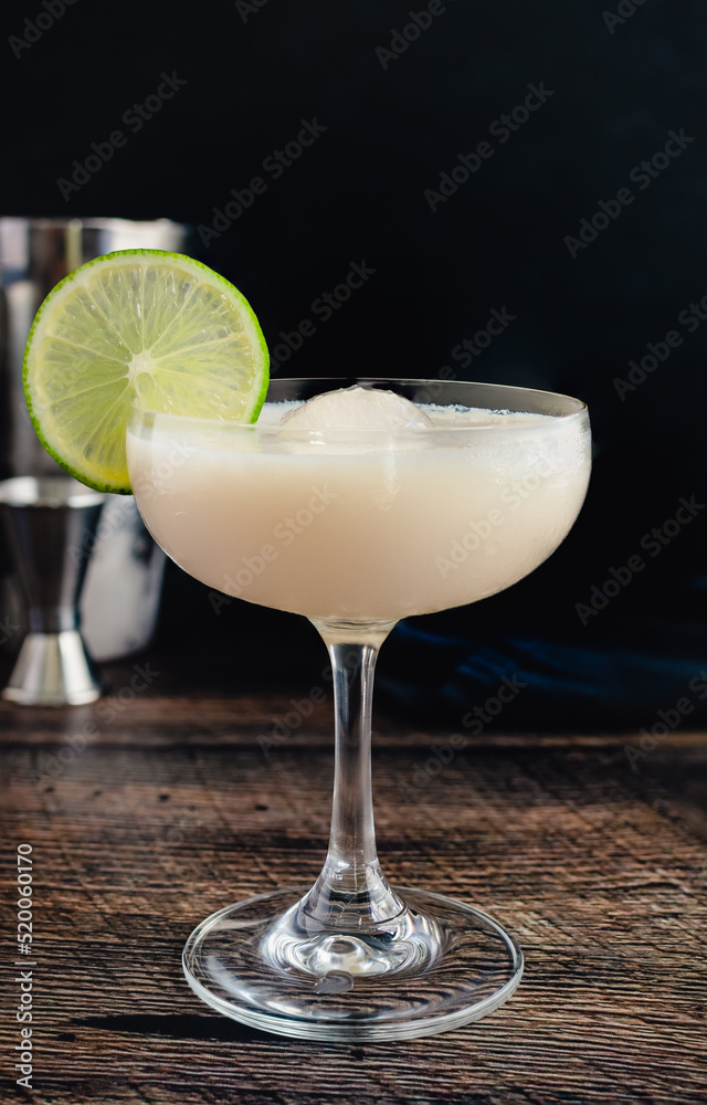 White Chocolate Gimlet Gin Cocktail with Ice Sphere: Cocktail made with gin, lime cordial, and white chocolate liquer in a coupe glass White Chocolate Gimlet Gin Cocktail with Ice Sphere: Cocktail made with gin, lime cordial, and white chocolate liquer in a coupe glass