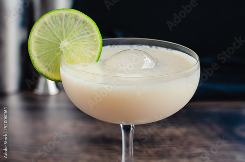 White Chocolate Gimlet Gin Cocktail with Ice Sphere: Cocktail made with gin, lime cordial, and white chocolate liquer in a coupe glass