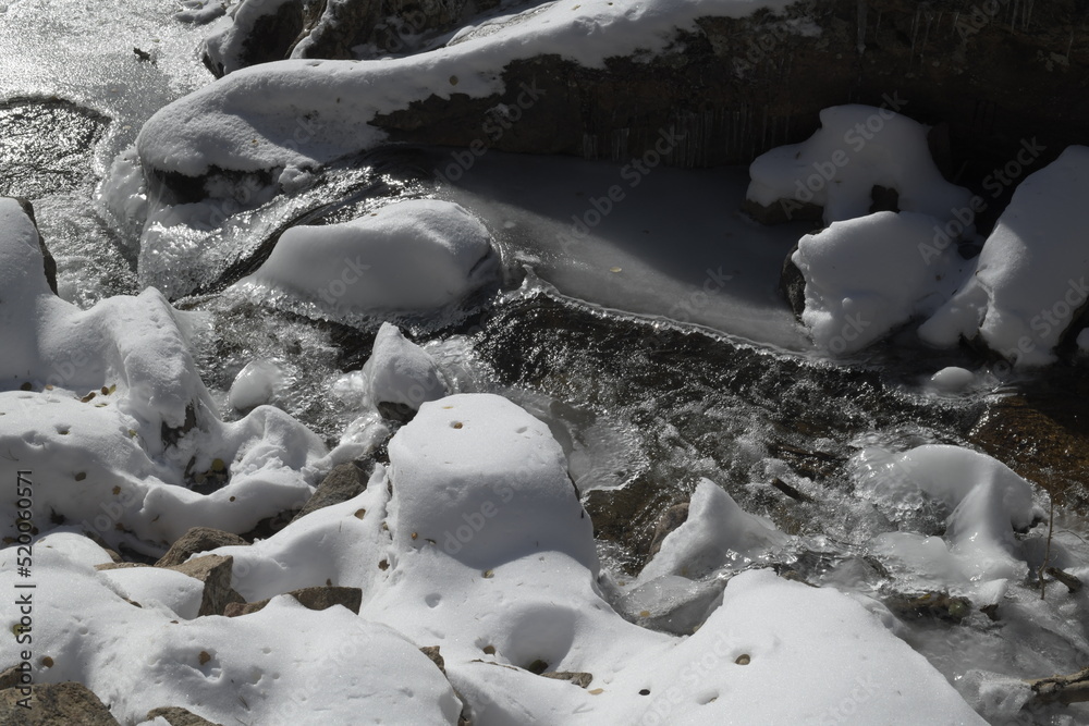 rocks covered in snow by a frozen river in the Rocky Mountains rocks covered in snow by a frozen river in the Rocky Mountains