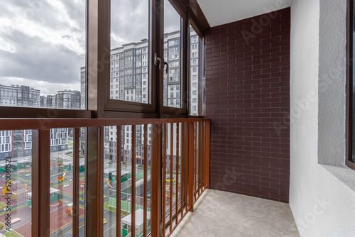 Glazed balcony with transparent railing and brick wall in cloudy weather