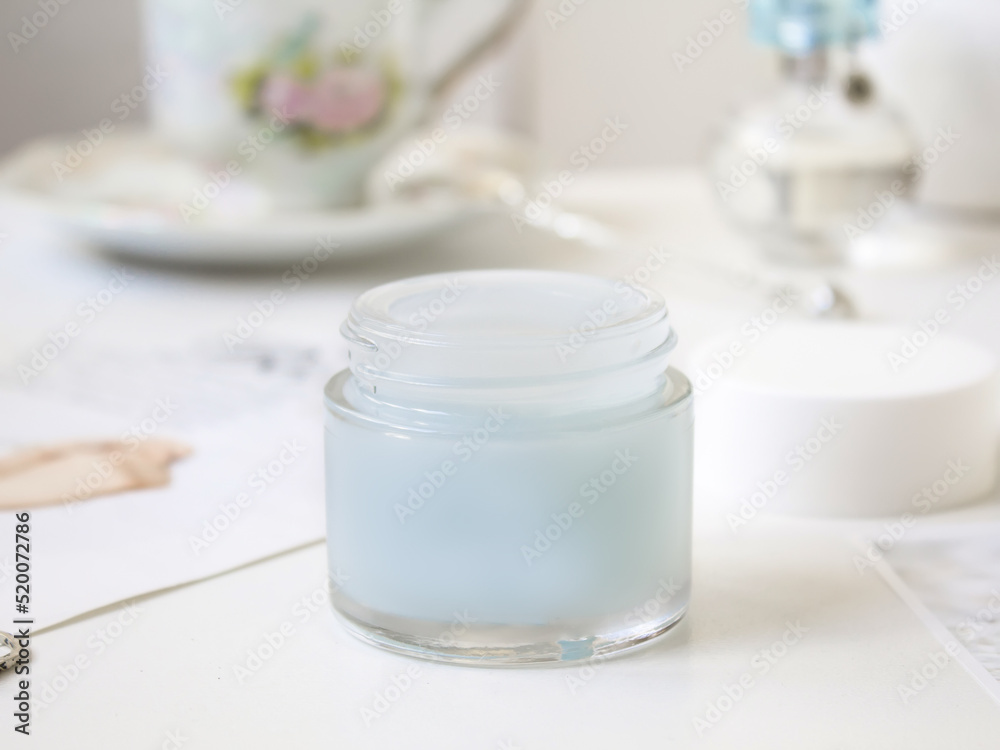 Blue bottle with cosmetic cream on a white blurred background with a cup Blue bottle with cosmetic cream on a white blurred background with a cup