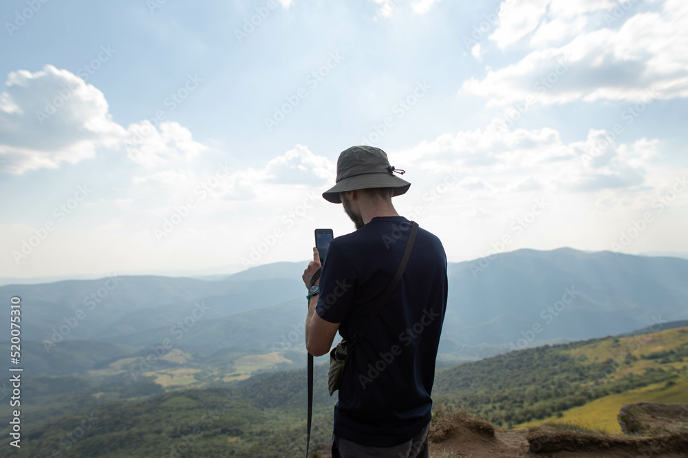 a man takes a photo on a mobile phone in the mountains a man takes a photo on a mobile phone in the mountains