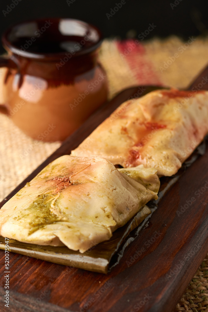 Ranchero tamales with red and green sauce placed on their banana leaf