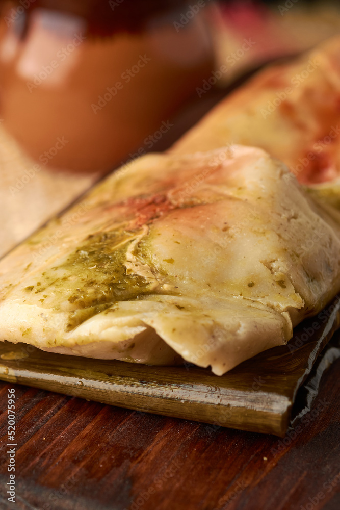 Ranchero tamales with red and green sauce placed on their banana leaf