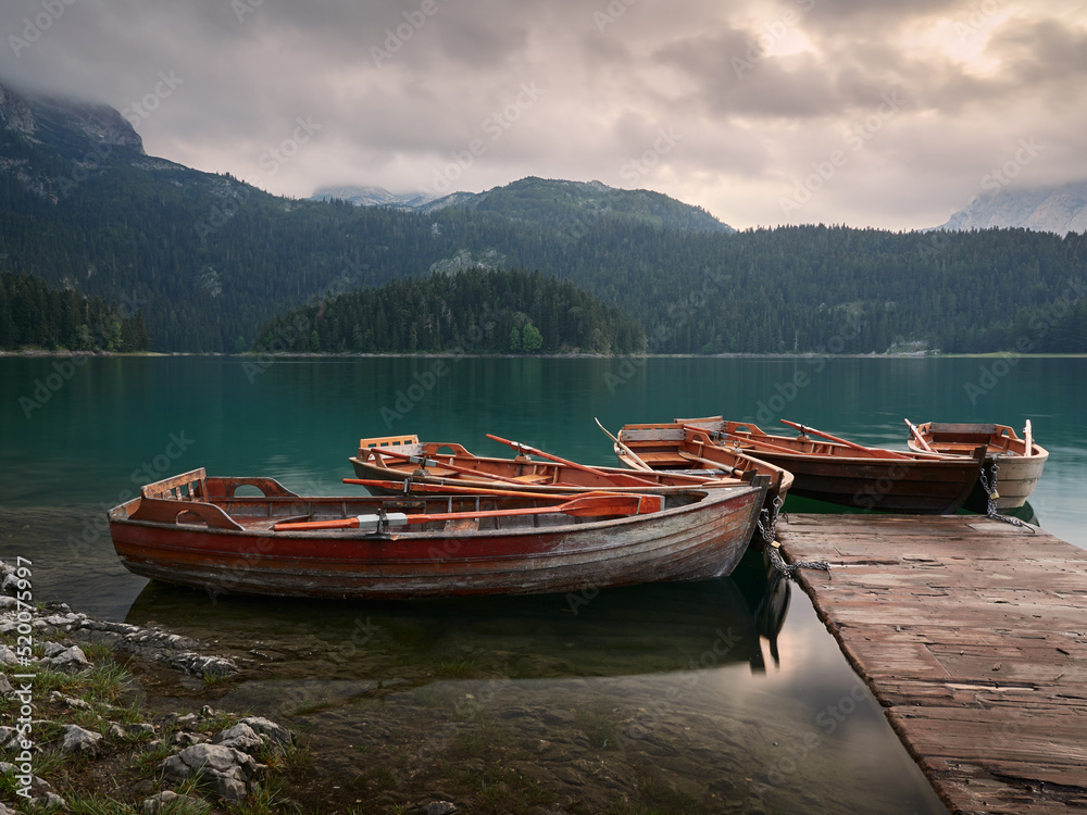 Black Lake in Montenegro. Moored wooden boats and mountains in the background. Sunset in the Durmitor National Park.